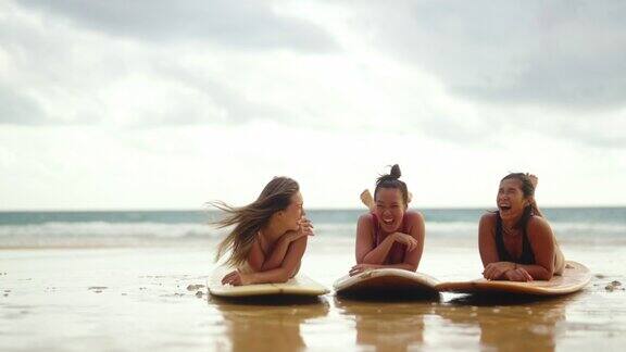 4K一群亚洲女子泳装躺在冲浪板在热带海滩在夏天的夕阳