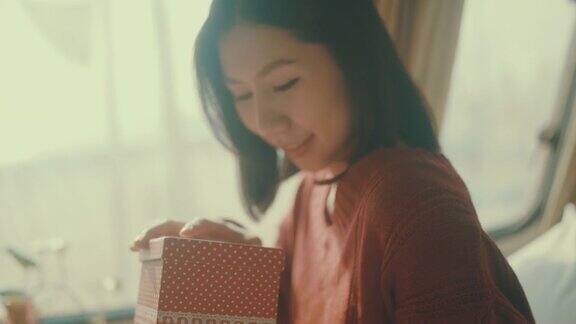 亚洲妇女高兴时她打开一个礼物盒在圣诞节活动