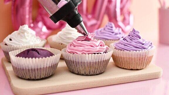 用淡粉色奶油装饰天鹅绒紫色可爱的杯形蛋糕制作杯子蛋糕的特写