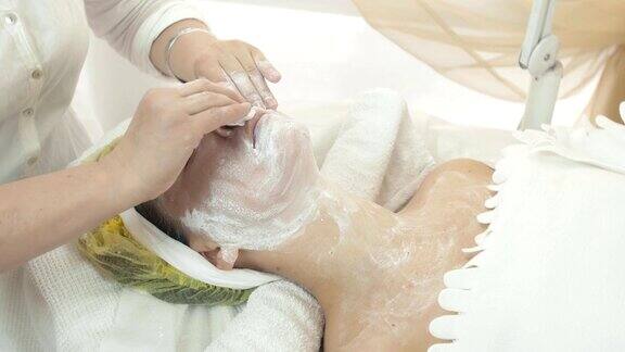 美容师在美容院用化妆棉擦拭女性脸上的面膜