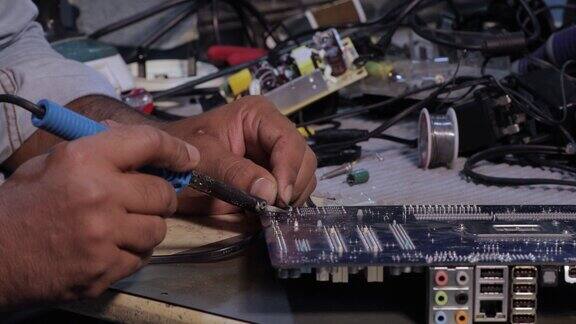 技术人员正在用烙铁修理电脑电路板上的电子元件