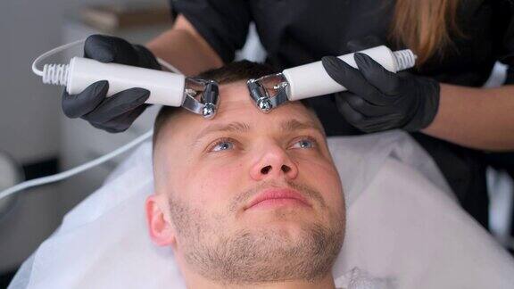 一位美容师使用现代设备为一位男士的面部进行恢复活力的按摩