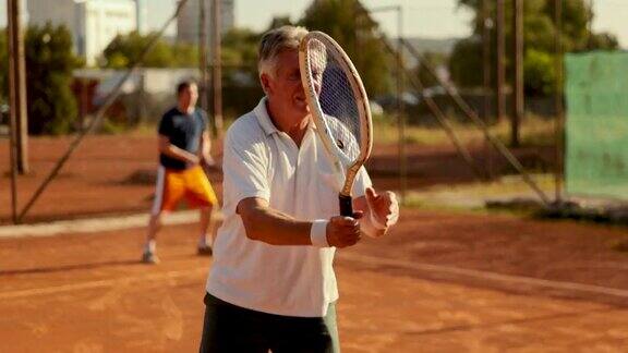 活跃的父亲和他刚成年的儿子一起在红土场上进行户外网球训练