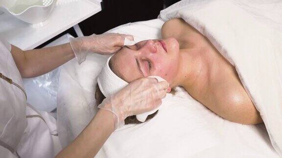 美容师用化妆餐巾清洁客户的脸和脖子