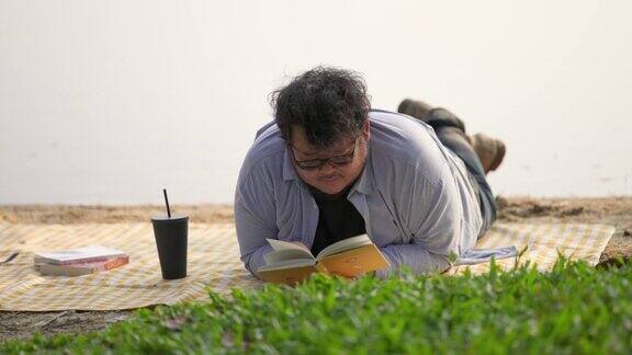 一个年轻人躺在湖边读文学作品