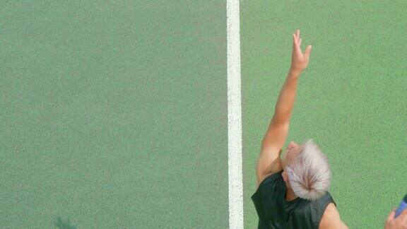 一位头发灰白的年轻男子网球运动员用慢动作发球