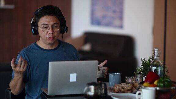一位亚洲华人中年男子在餐厅吃早餐早上用笔记本电脑回复电子邮件