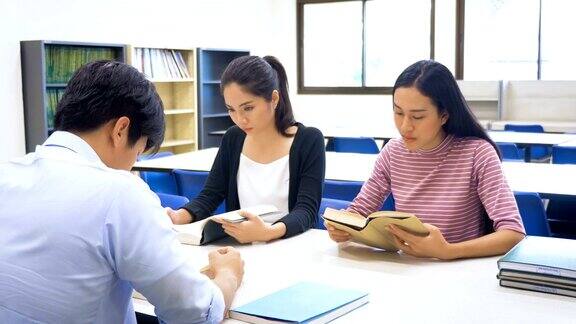 一群年轻的亚洲学生带着书在大学图书馆做研究学习教育和学校理念