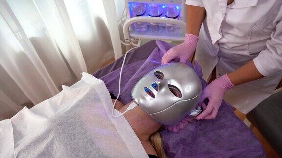 一位美容师给一位女士戴上led面膜护肤品光线疗法治疗