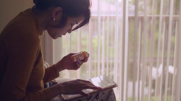 年轻的亚洲女人拿着药瓶在卧室里讲手机