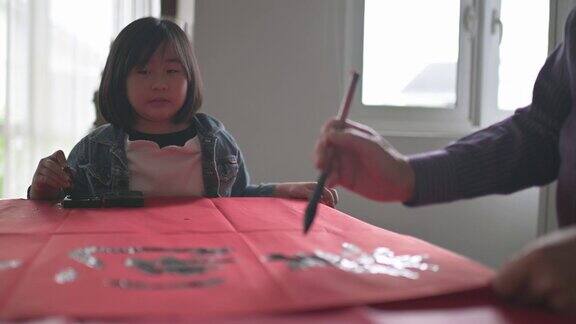 亚洲华裔年轻女孩帮助和学习她的祖父写中国书法