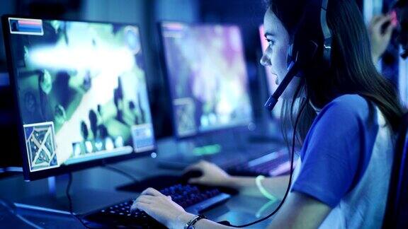 职业女性玩家在她的电脑上玩MMORPG策略电子游戏她参加网络游戏比赛在家里玩或在网吧玩她戴着游戏耳机