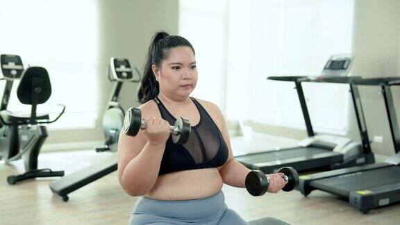 美丽的亚洲超重女子在乡村健身房里练习用手举哑铃来锻炼手臂肌肉胖乎乎的女人打算通过锻炼来减肥生活方式及运动概念
