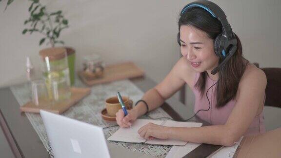 亚洲华裔美女在厨房用笔记本电脑参加在线课程视频通话