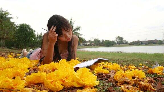 亚洲女孩躺在草地上看书