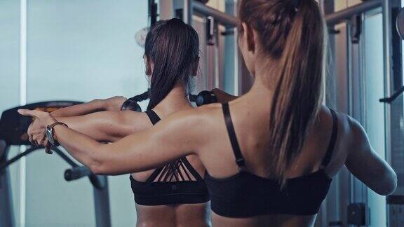 年轻的亚洲女性在健身房里锻炼在私人教练的指导下锻炼肌肉和力量健身在健身房锻炼