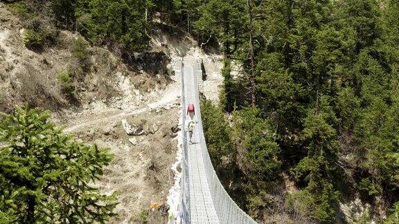 游客在尼泊尔喜马拉雅山徒步旅行时穿过吊桥