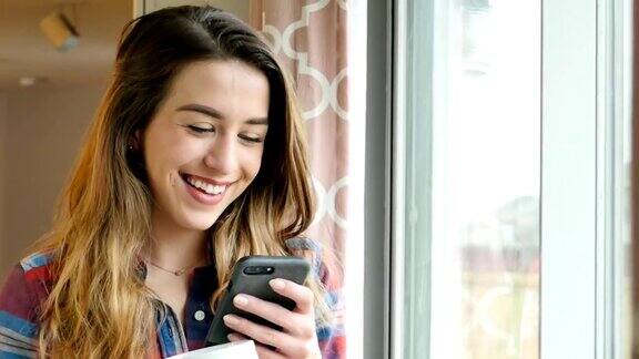 快乐的年轻女子微笑和大笑因为她使用智能手机