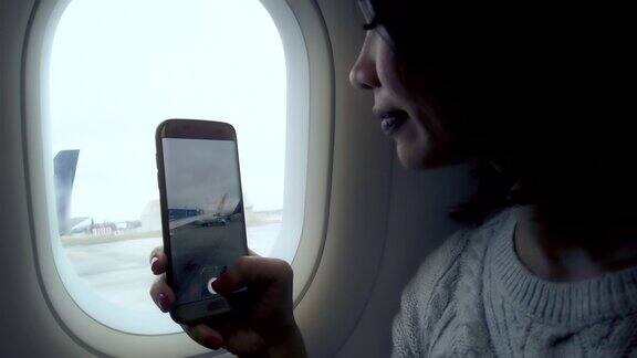亚洲女人从飞机上用手机拍照