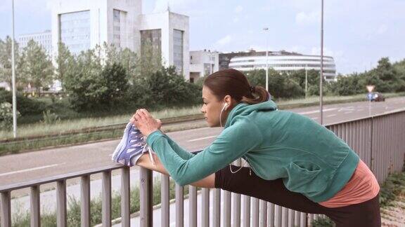 一名女性慢跑者在篱笆上伸展她的腿