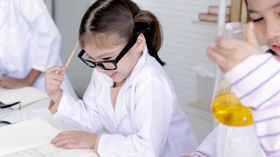科学教育在实验室小学生在教室里可爱的小学生女孩专注于化学实验和写报告科学老师教学生