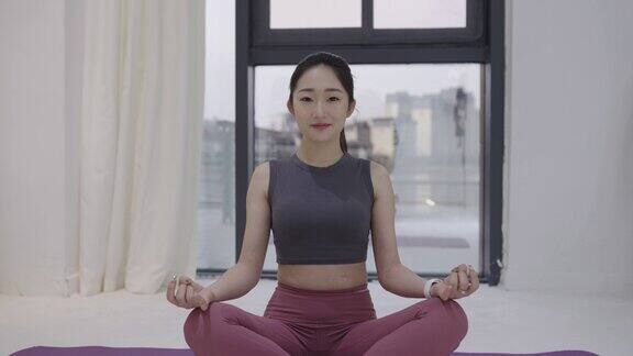 年轻的亚洲女性穿着瑜伽裤在瑜伽垫上练习瑜伽