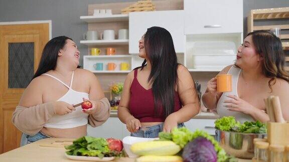 一群快乐的亚洲大码女性一边做饭一边唱歌跳舞在家里的厨房里准备晚餐身体的积极性身体接受概念