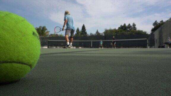 一个网球的特写镜头背景是人们在打网球