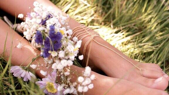 女孩的脚在绿草和鲜花和脚珠宝