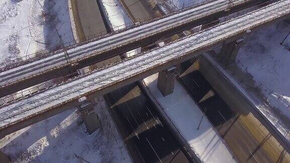 悬索桥高于冬季公路和汽车交通的雪道空中景观无人机拍摄高速公路上移动的火车桥和汽车