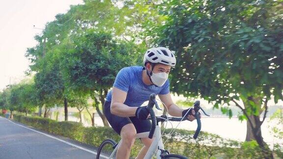 亚洲年轻运动男性戴口罩在公园里骑自行车迷人的运动员肌肉男运动服装骑自行车锻炼的健康和保健健康的晚上