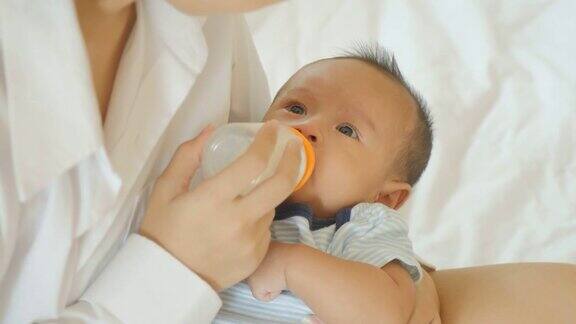 年轻的亚洲母亲在家用奶瓶喂男婴