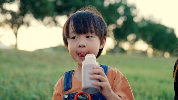 饥饿的男孩在家庭野餐时喝牛奶