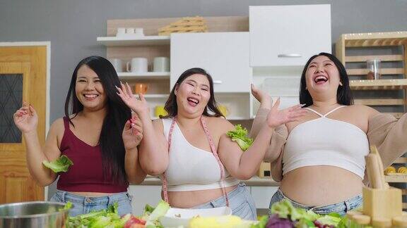 一群快乐的胖乎乎的女性朋友向空中扔蔬菜三个亚洲大码女人把蔬菜扔向空中对自己的身体很有信心健康食物概念