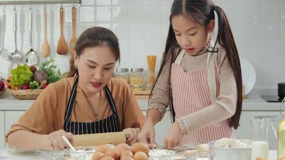 年轻的母亲和小女孩在厨房准备食物他们喜欢一起做饭