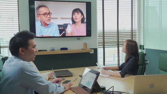 亚洲白领与公司员工进行视频会议会议讨论在会议室董事会与外国投资者进行视频会议公司并购业务会议