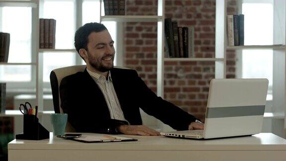 在办公室里拿着笔记本电脑微笑的男人