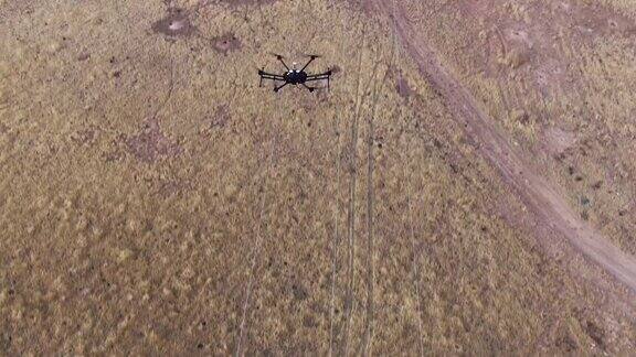 倾斜向上的六旋翼无人机鸟瞰图检查电力线上方的草地与土路下面和山在背景在科罗拉多西部大峡谷