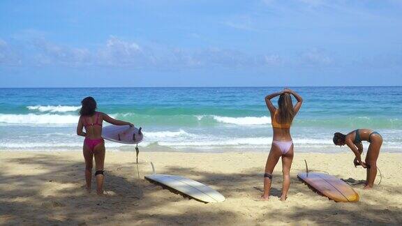 一群亚洲女子穿着冲浪板安全绳一起在海里冲浪