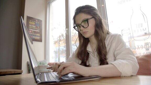 褐发白种女人戴着眼镜在咖啡馆工作带着笔记本电脑4K