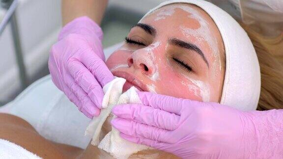 美容师在手套擦拭女人脸上的面具特写肖像
