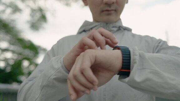 年轻的亚洲运动员在公园运动后使用智能手表