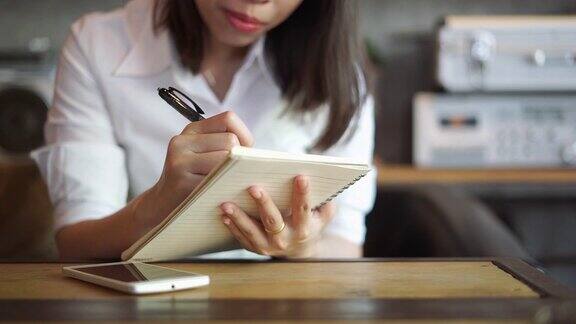 年轻女子使用智能手机咖啡杯和笔记本