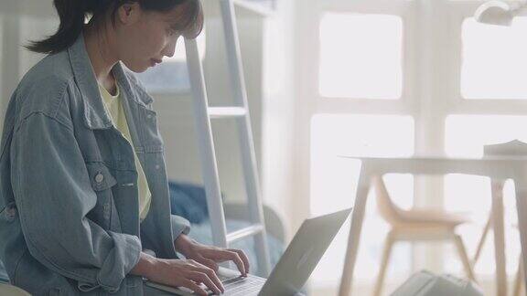 亚洲女生使用笔记本电脑在线学习课程在线学习准备学校考试坐在宿舍的桌子上做笔记