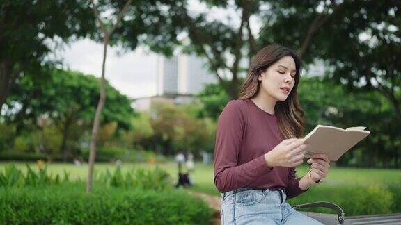 年轻的亚洲妇女在公园看书放松的时刻