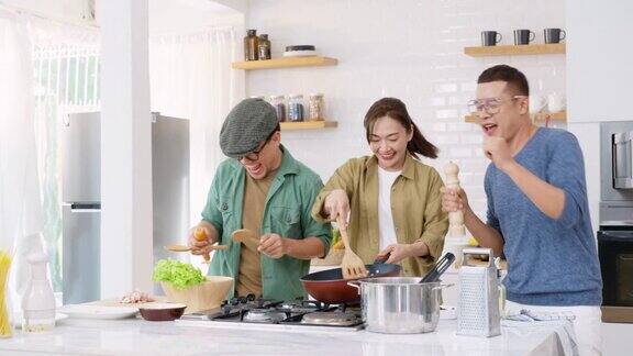 一群亚洲男女朋友在家里的厨房里一边做意大利面一边聊天