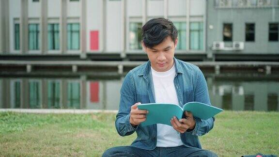 亚洲人大学的学生坐在校园草地上看快乐和在公园看书