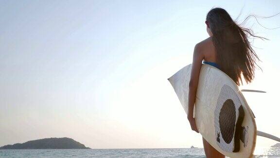 美丽性感的年轻女子冲浪女孩穿着比基尼与白色冲浪板在海滩上日落或日出假期iStock