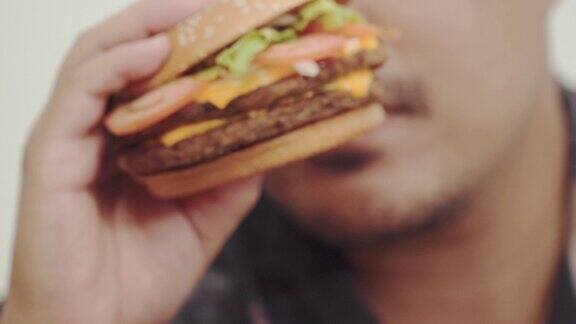 近距离拍摄的年轻人享受吃汉堡包享受不健康的饮食