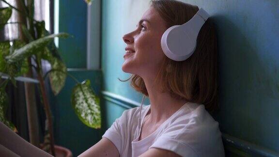 放松的女孩在地板上戴着耳机享受音乐